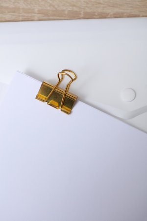 Golden clip with white empty sheet of paper on the tableの写真素材