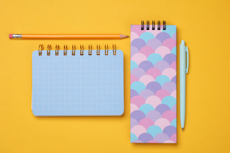 Notepads with pencils on a yellow background. Top view