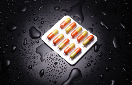 Blister of tablets on a black background with water drops