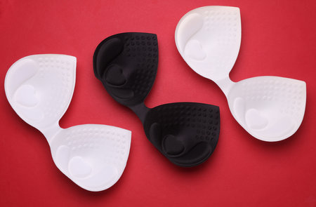 Black and white invisible bras on red background. Top view