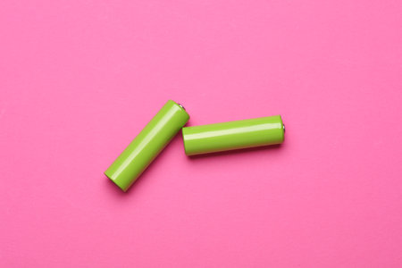 Green AA batteries on a pink backgroundの写真素材
