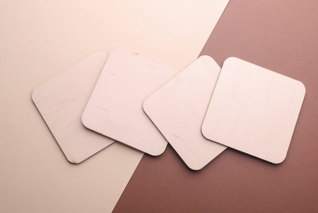 Wooden square drink coasters on beige brown background