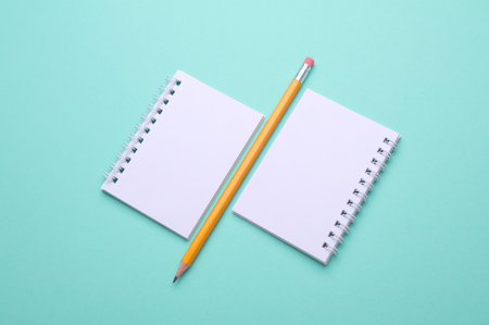 Blank white spiral notebooks with pencil on mint green backgroundの写真素材