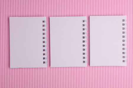 Group of white blank spiral notebooks on pink background