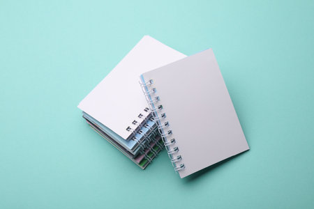 Stack of white blank spiral notebooks on mint green backgroundの写真素材