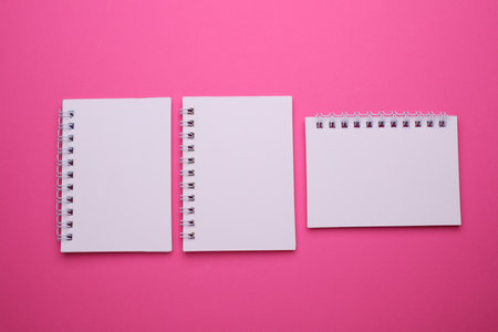 Group of white blank spiral notebooks on pink backgroundの写真素材