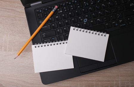 Laptop and white blank spiral notebooks with pencil on table. Education, business concept. Top view