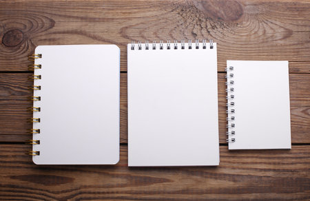 Group of white blank spiral notebooks on wooden backgroundの写真素材