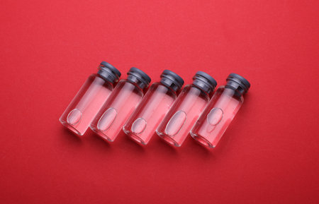 Medical glass vials with liquid on a red background