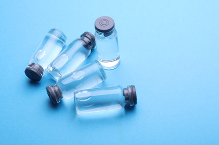 Medical glass vials with liquid on a blue backgroundの写真素材