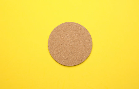 Cork coaster for drinks on a yellow background