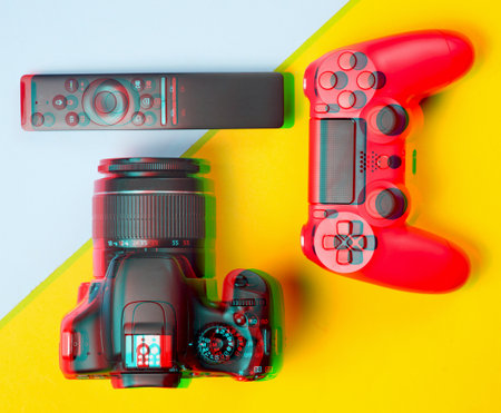 Glitch effect modern gadgets and devices on a colored paper background. Dslr camera, remote, gamepad. Top view.の写真素材