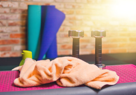 Training equipment. Metal dumbbells, towel, mat, bottle of water against the background of concrete wall.の写真素材