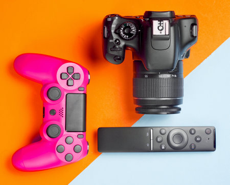 Modern gadgets and devices on a colored paper background. Dslr camera, remote, gamepad. Top view.