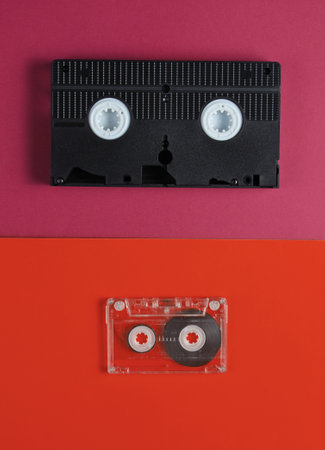 Pop culture media 80s. Audiotape, videotape on orange red background. Top viewの写真素材