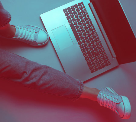 Night online work at laptop. Freelance concept. A woman is sitting on the floor with laptop. Duotone effectの写真素材