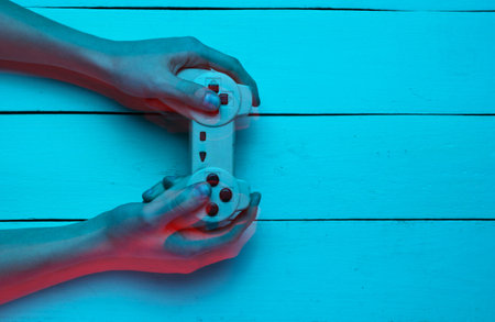 Concept gamer. Nightlife. Leisure. Hand holds gamepad on blue wooden background. Glitch effectの写真素材