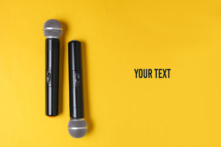 Two wireless microphone on yellow background. Flat lay. Top view. Copy space
