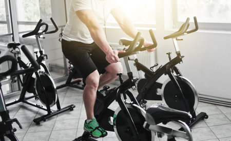Healthy lifestyle concept. Young sporty man in white t-shirt and shorts is exercising bike at...