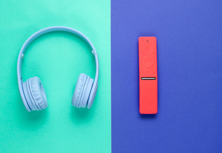Modern gadgets on a mint blue background. Wireless headphones, remote controller. Top view