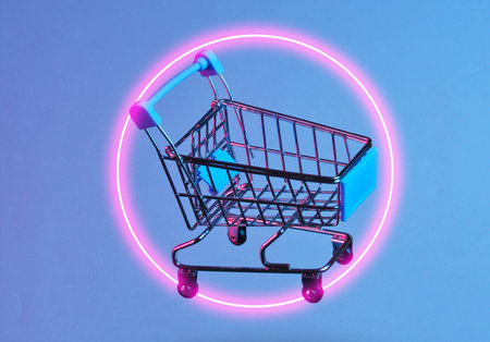Minimalism shopping concept. Toy shopping trolley, neon night. Photo with shadow