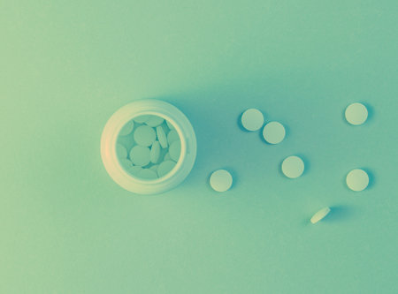 Minimalism medical concept. Small bottle with white pills, holographic blue light. Top viewの写真素材