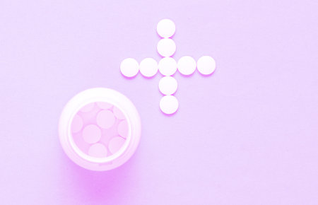 Bottle with pills, white pills in the shape of a cross on. Top view. Minimalism medical concept. Helping hand/ Tonned photoの写真素材