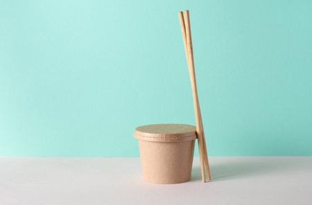 Eco cardboard round food box with chopsticks on table, turquoise backgroundの写真素材