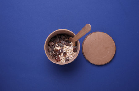 Oatmeal with raisins in a disposable craft box on a blue background.の写真素材
