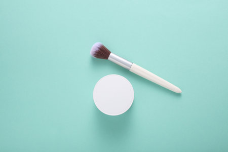 White cream jar and makeup brush on mint green background. Top viewの写真素材