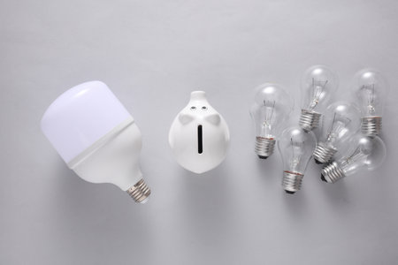 LED and ncandescent light bulbs with piggy bank on gray background. Saving electricity