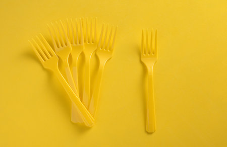 Set of plastic forks on yellow background
