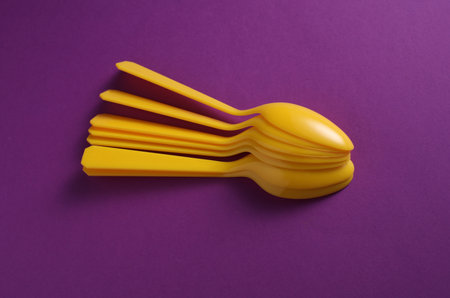 Yellow Plastic spoons on purple background.の写真素材