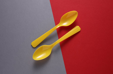 Yellow Plastic spoons on gray red background. Minimalism. Creative layoutの写真素材