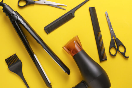 Flat lay hairdressing tools and accessories for hair styling on yellow background. Top viewの写真素材