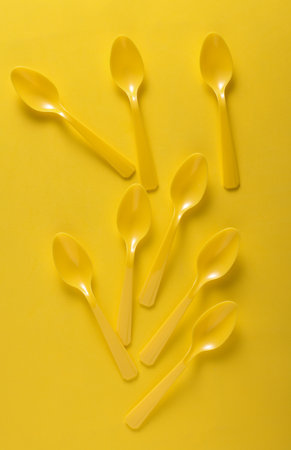 Set of plastic spoons on yellow backgroundの写真素材
