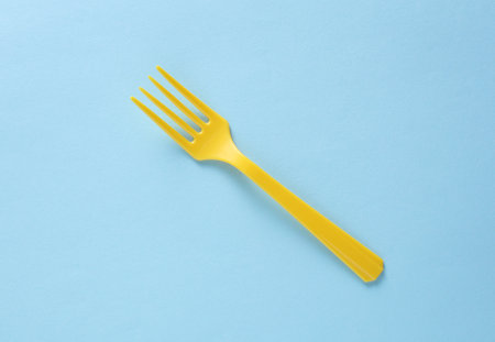 Yellow Plastic fork on blue background close upの写真素材