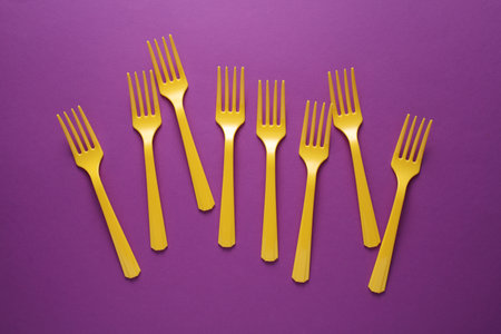 Yellow Plastic forks on purple background.の写真素材