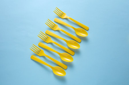 Yellow Plastic forks and spoons on blue background