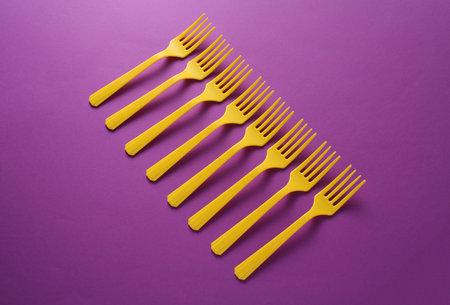 Yellow Plastic forks on purple background.
