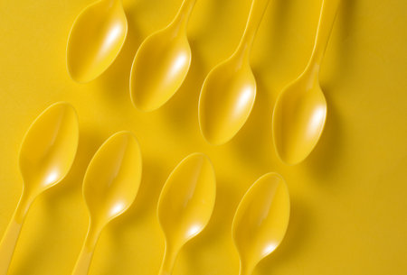 Set of plastic spoons on yellow backgroundの写真素材