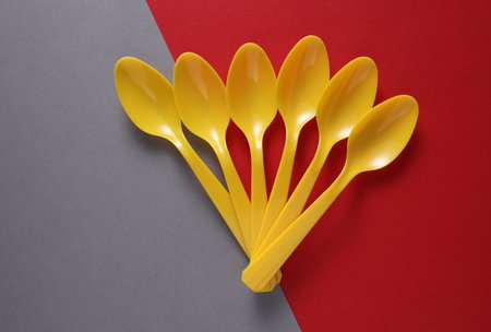 Yellow Plastic spoons on gray red background. Minimalism. Creative layoutの写真素材
