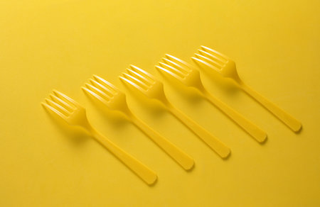 Set of plastic forks on yellow backgroundの写真素材
