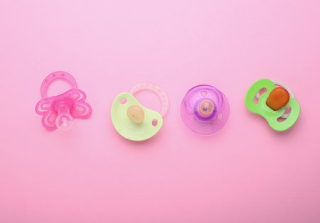 Newborn baby's pacifiers on a pink background. Top viewの写真素材