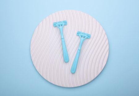 Blue disposable razors on round podium, blue background. Top viewの写真素材