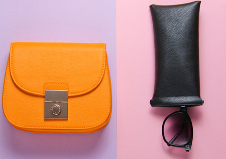 Fashionable female accessories on pastel paper background. Trendy leather wallet, bag, sunglasses in protective case. Top viewの写真素材