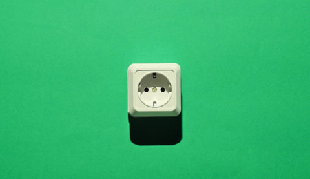 White plastic power socket on green background. Minimalism