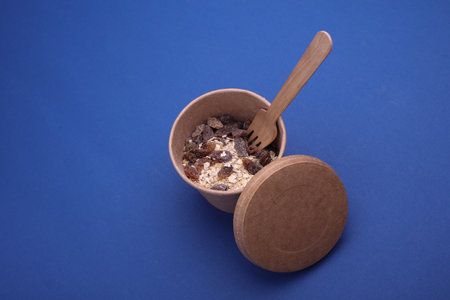 Oatmeal with raisins in a disposable craft box on a blue background.の写真素材