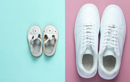 Father's day concept. Adult white sneakers and children's sandals on purple blue background. Top viewの写真素材