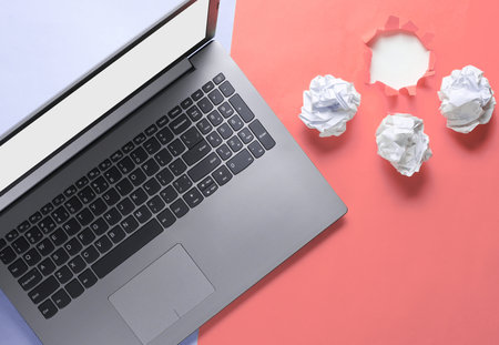Minimalistic business concept. Notebook, crumpled paper balls, on blue pink background with a torn hole for copy spaceの写真素材